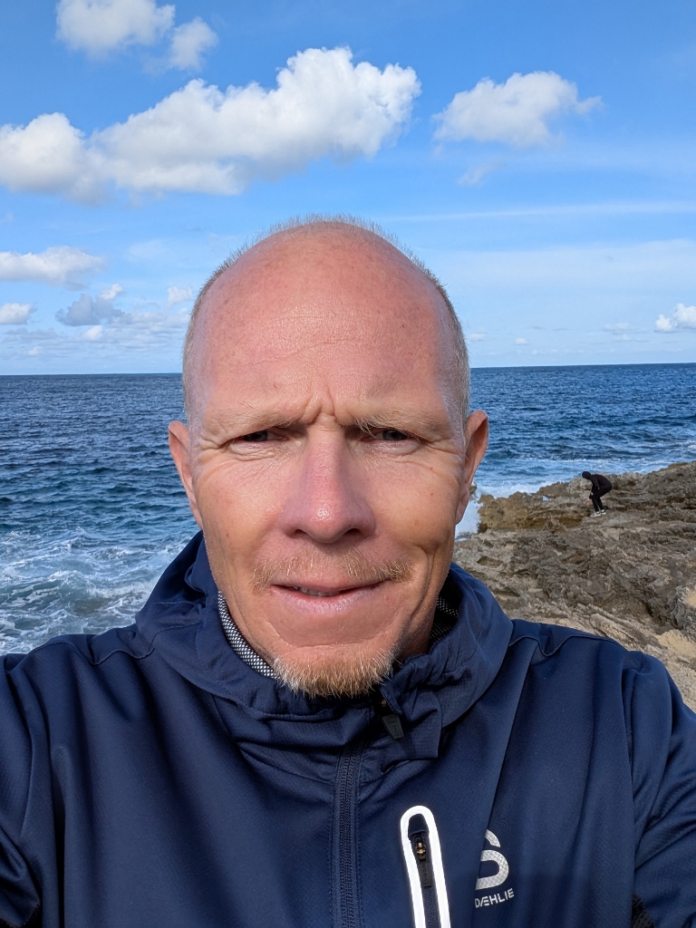 Carsten Sacher an der felsigen Küste, Meer im Hintergrund